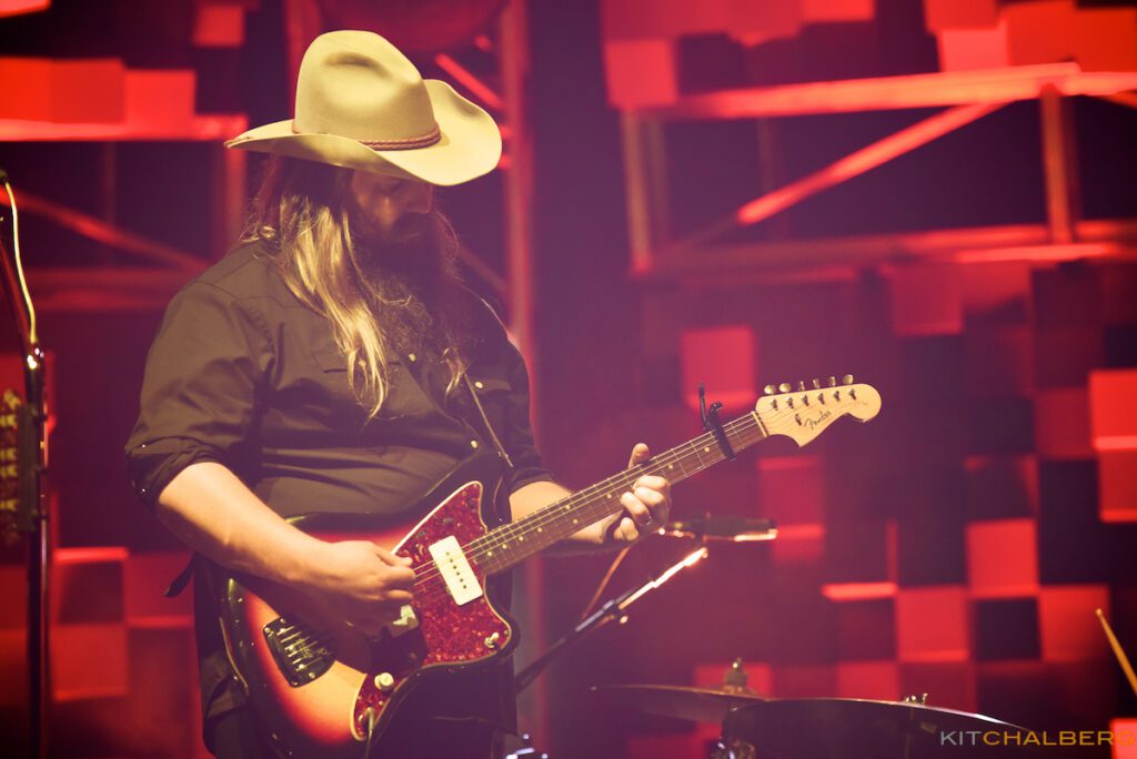 Musician playing electric guitar on stage.