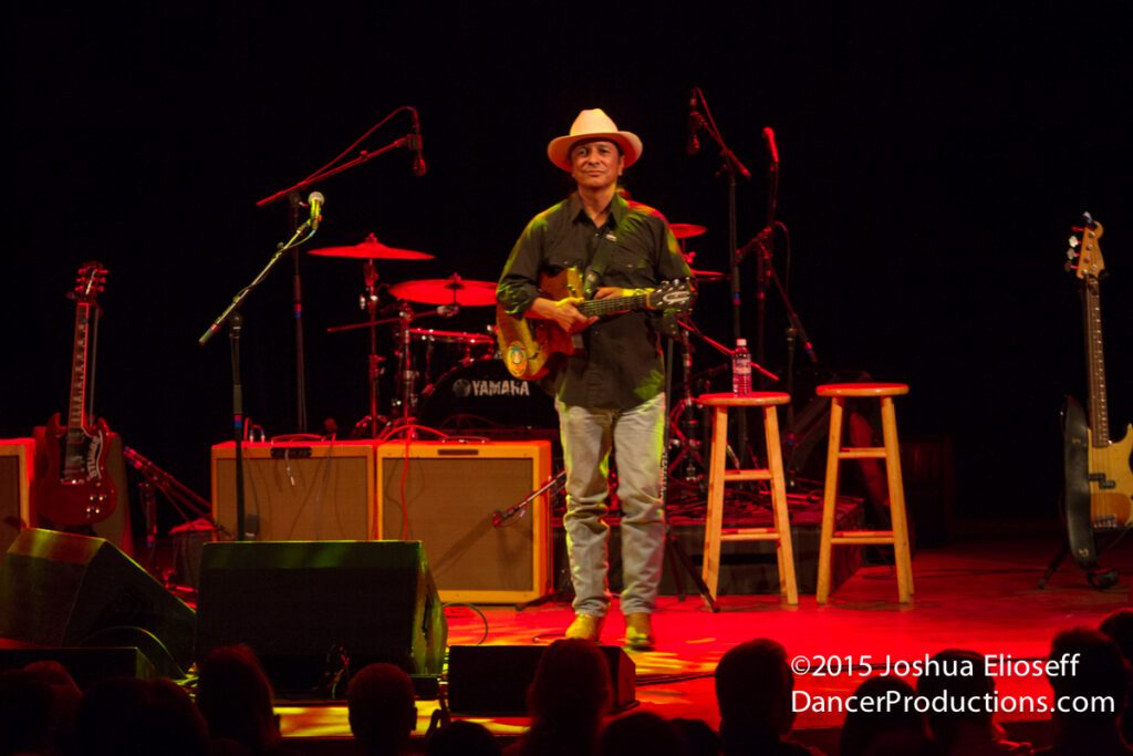Musician performing on stage with guitar.