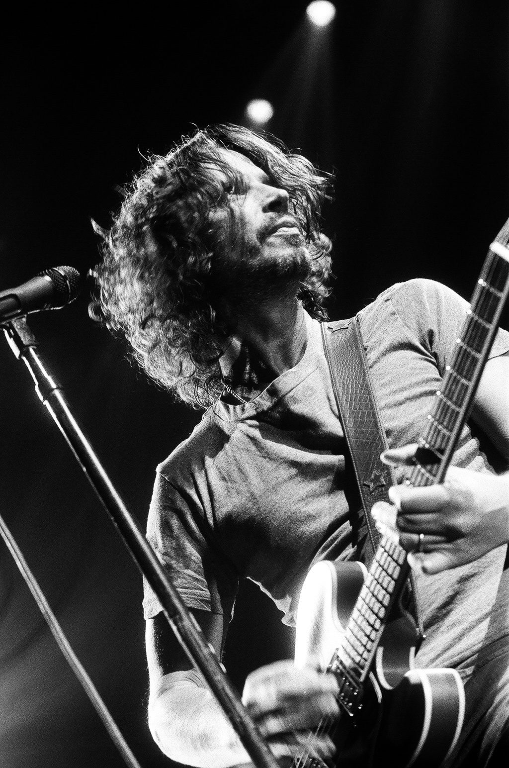 Musician playing guitar on stage, dramatic lighting.