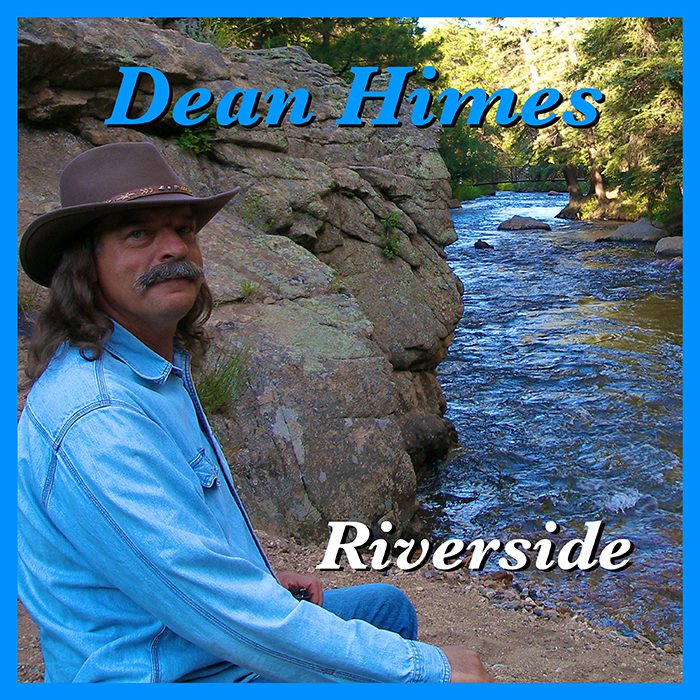 Man sitting by a scenic riverside.
