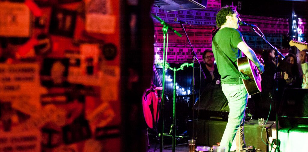 Musician performing live on stage with guitar.