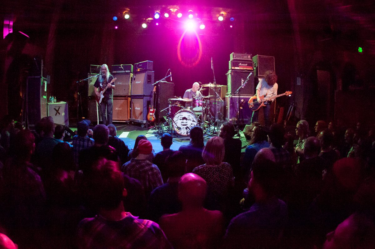 Rock band performing on stage with audience.