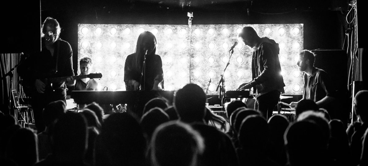 Band performing on stage with bright lights.