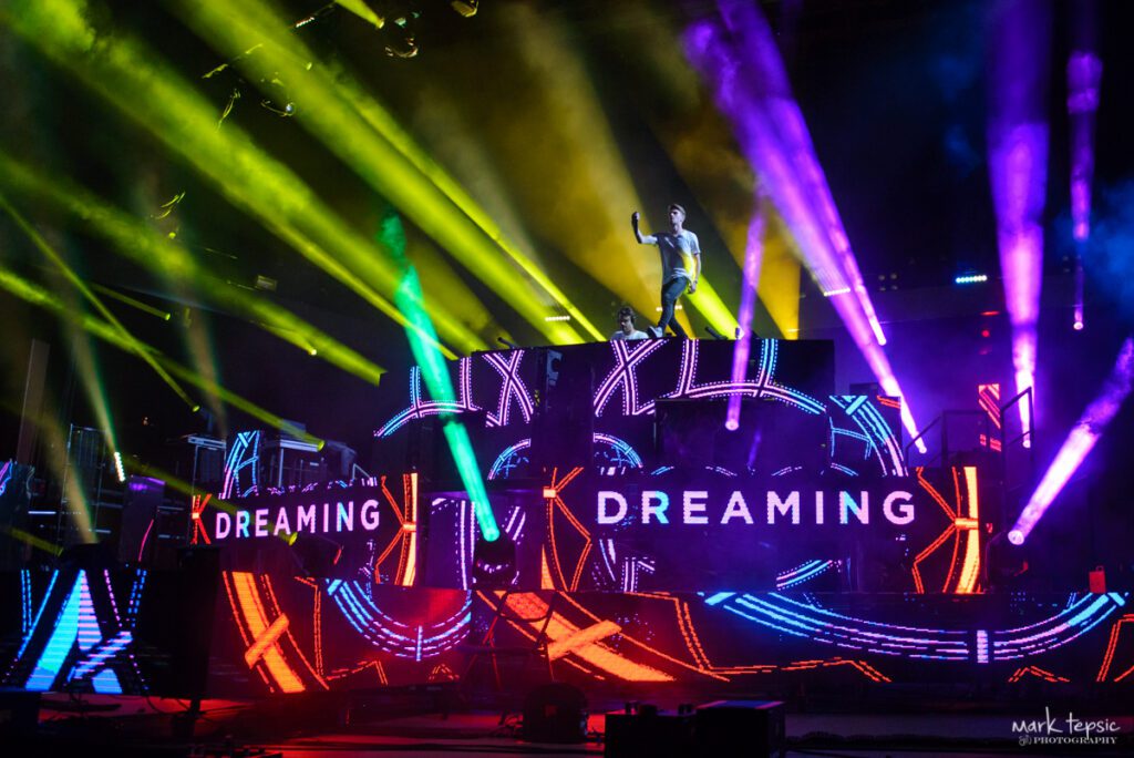 DJ performing on colorful stage with lights.