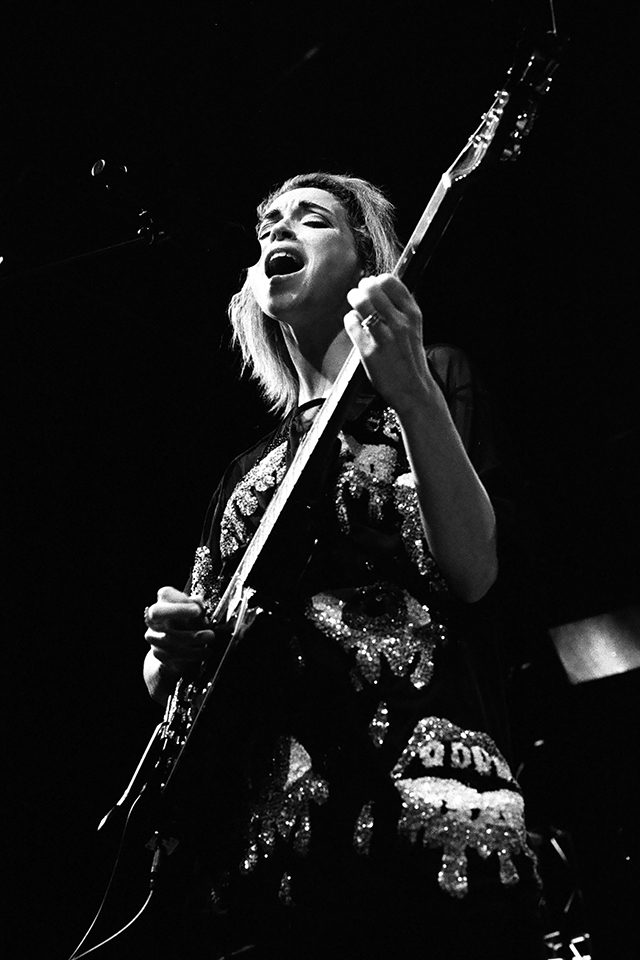 Musician singing and playing guitar on stage.