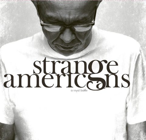 Man wearing "Strange Americans" t-shirt, looking down.