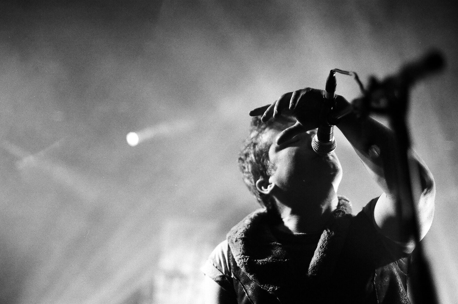 Singer performing passionately on stage, black and white.