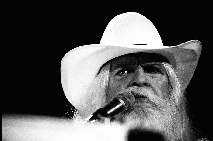 Man in white hat singing on stage.