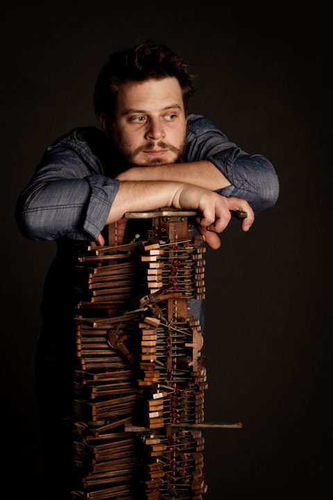 Man leaning on a wooden structure thoughtfully.