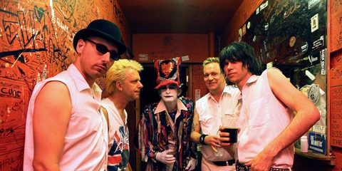 Band posing in graffiti-covered backstage area.