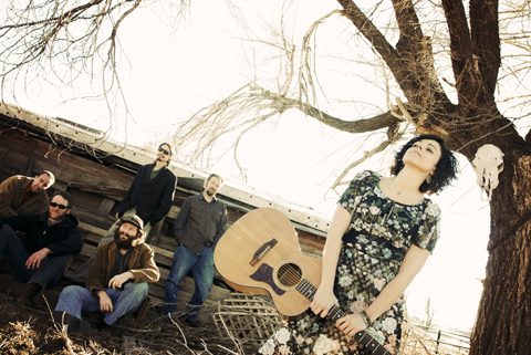 Band with guitar near tree and barn.