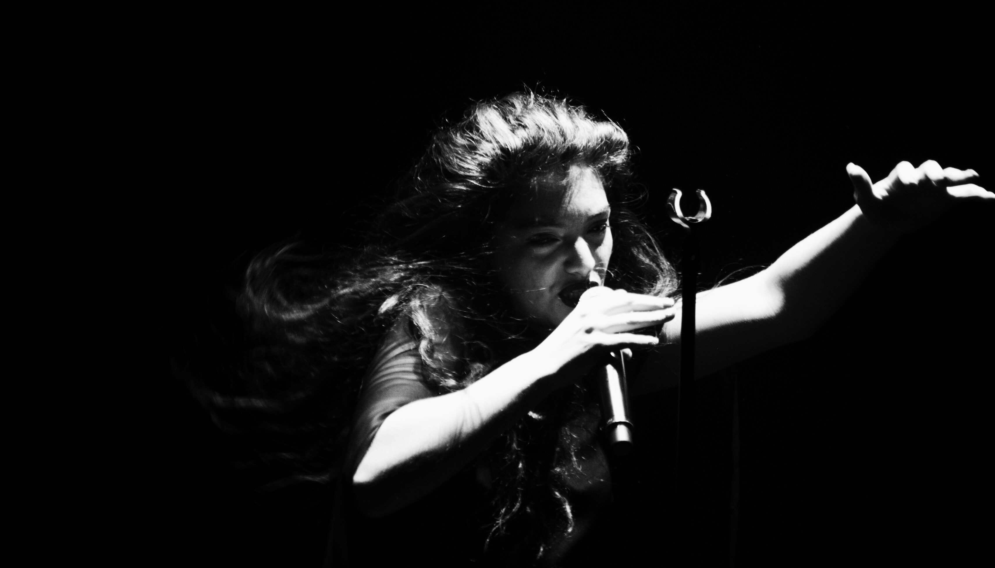 Singer performing passionately in dramatic lighting.