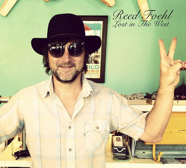 Man in sunglasses and hat making peace sign.