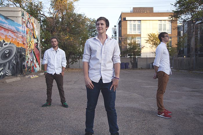 Three men standing in urban outdoor setting.