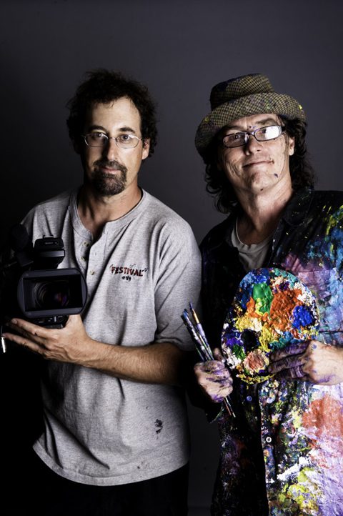 Two artists with camera and paint palette.
