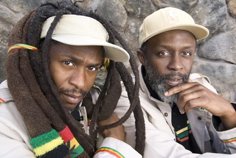 Two men wearing hats with dreadlocks.