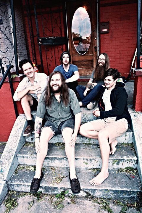 Five people sitting on outdoor steps, smiling.