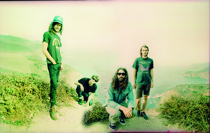 Four people posing on a scenic hill.
