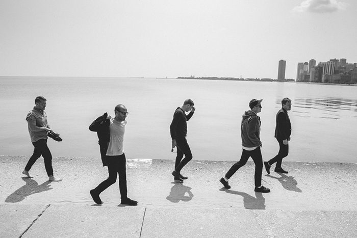 Five people walking along a lakeside promenade.
