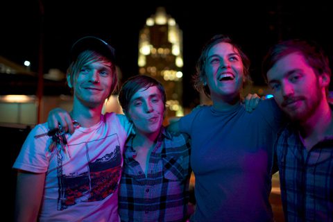 Group of friends smiling under colorful lights.