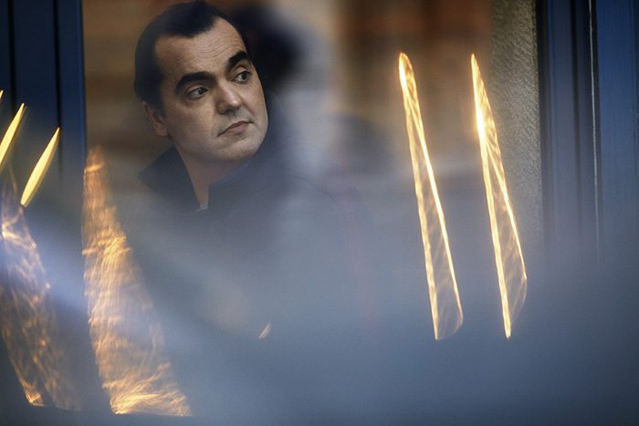 Man looking out window with blurred reflections.