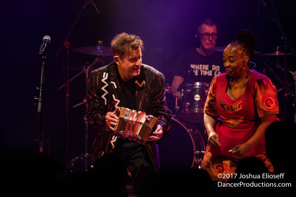 Musicians performing energetically on stage with instruments.
