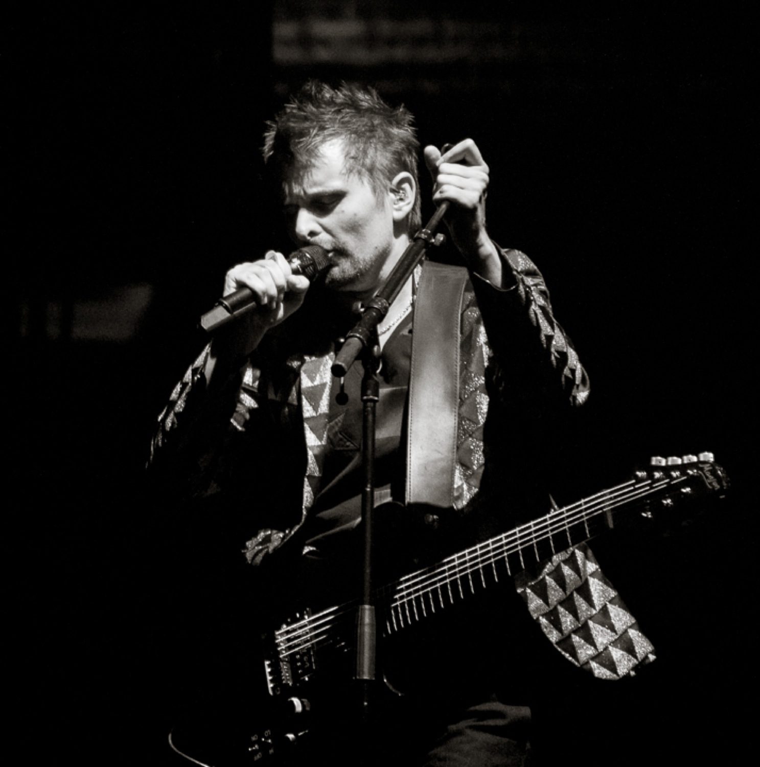 Singer performing with guitar on stage.