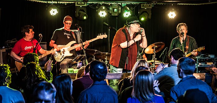 Band performing live on stage with audience.