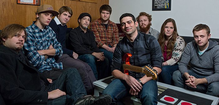 Group of people sitting with a guitar.