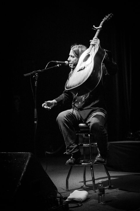 Musician performing with guitar on stage.