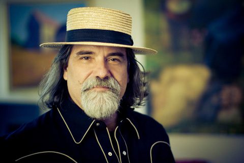 Man with hat and beard, wearing dark shirt.