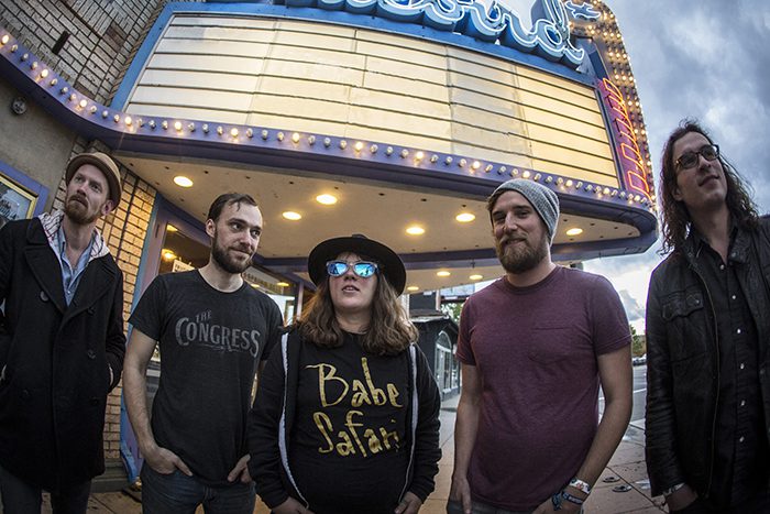 Five people standing under theater marquee.