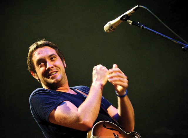 Singer performing with a microphone on stage.