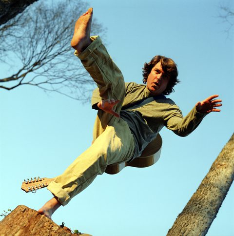 Person jumping with guitar in mid-air.