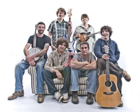 Band members with instruments on a couch.