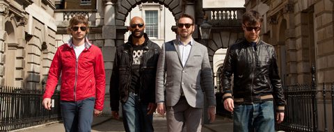 Four men walking in urban setting.