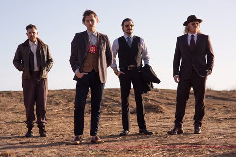 Four men in stylish, vintage-inspired outfits.