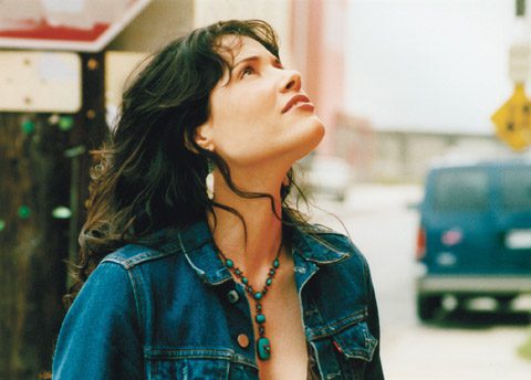Woman in denim looking up outdoors.