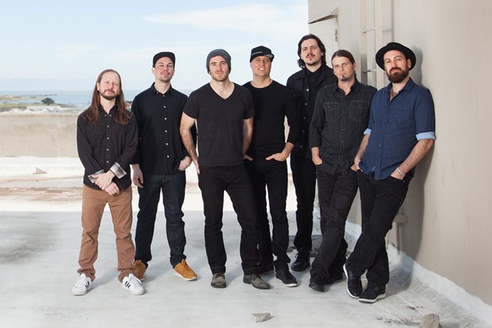 Seven men standing on a rooftop together.