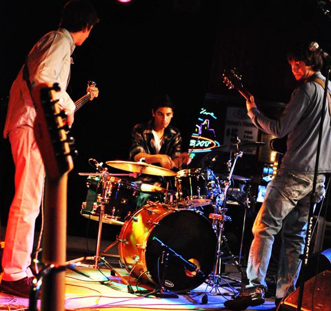 Band performing live on stage with instruments.
