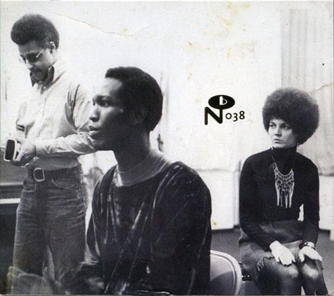 Three people sitting and standing indoors.