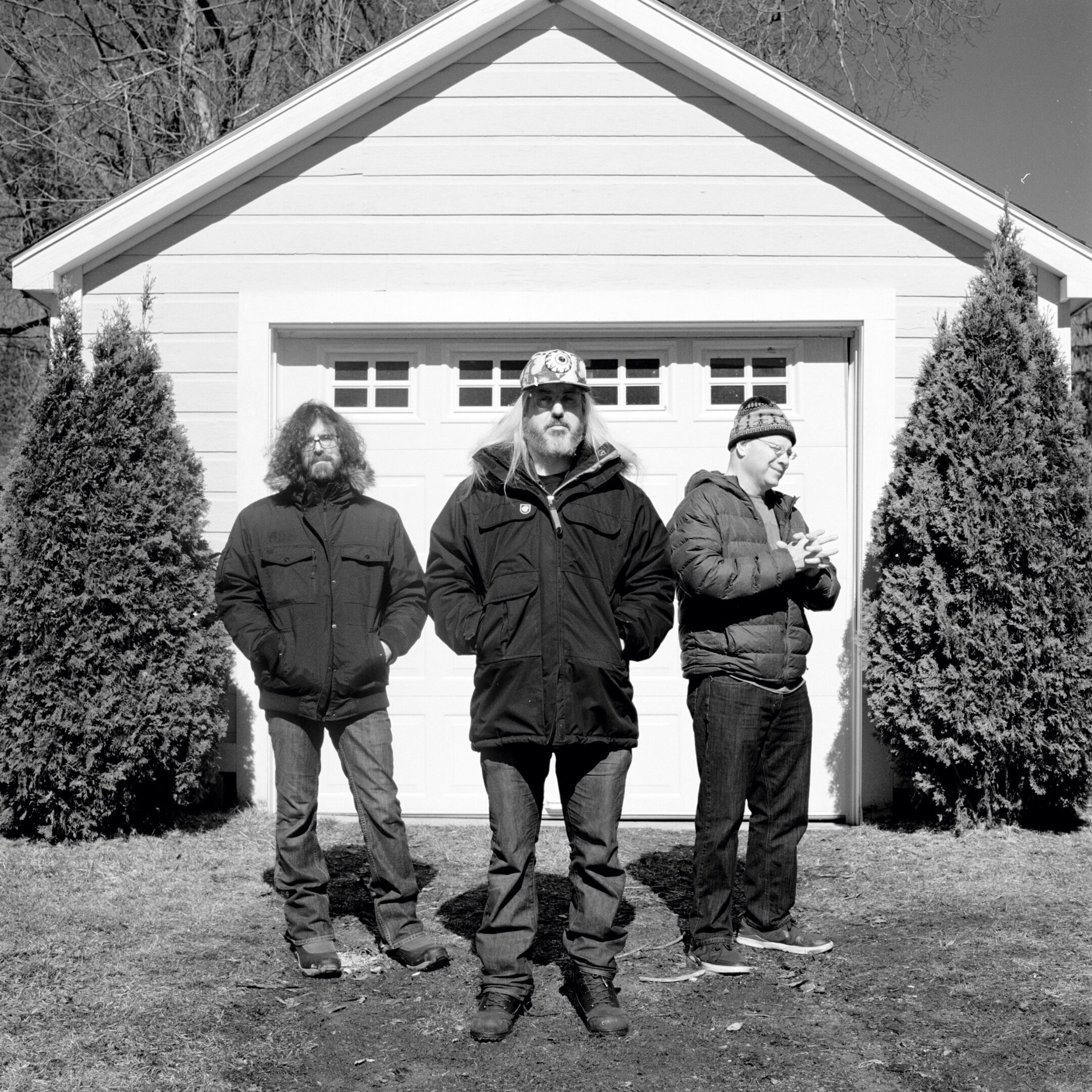 Three men standing in front of garage.