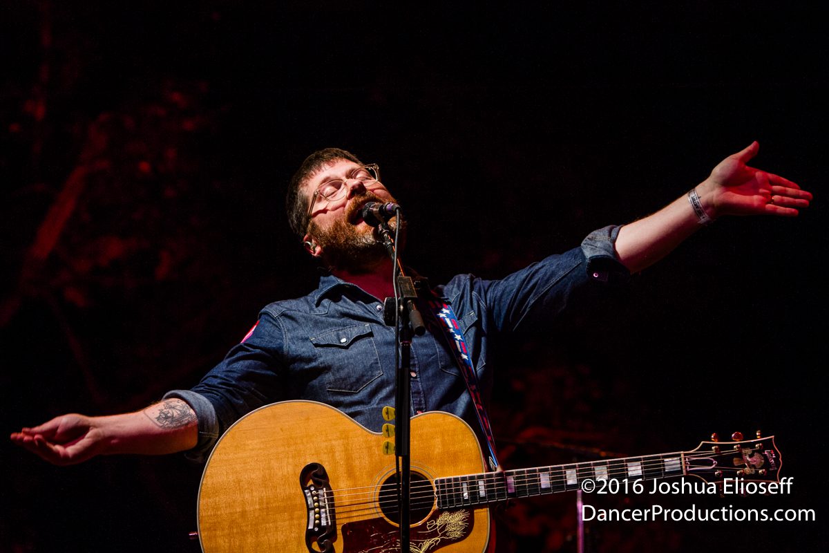 Musician performing with guitar on stage.