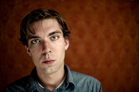 Man in denim shirt, orange background.