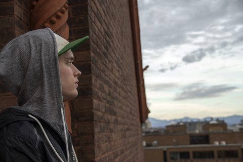 Person in hoodie looking at city skyline.