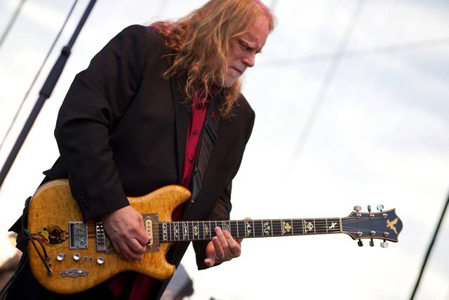 Guitarist performing on stage with electric guitar.