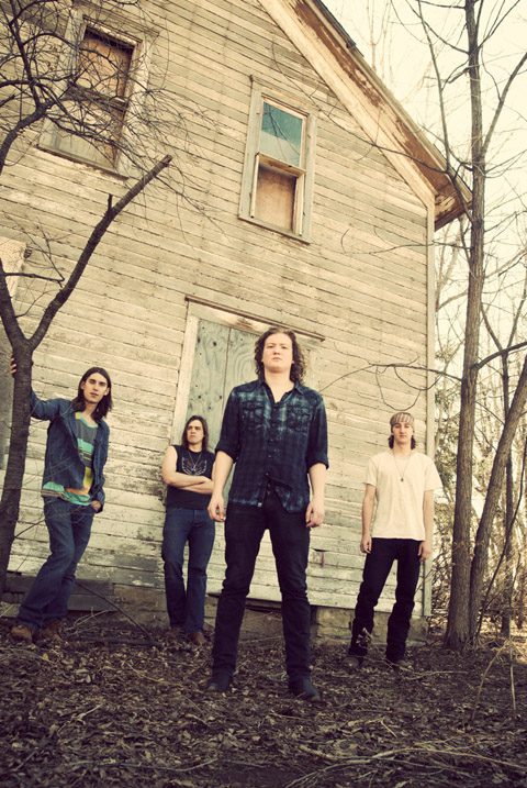 Four people standing by an old house.