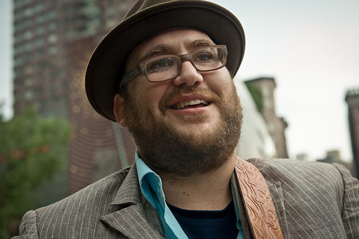 Man smiling in urban outdoor setting.