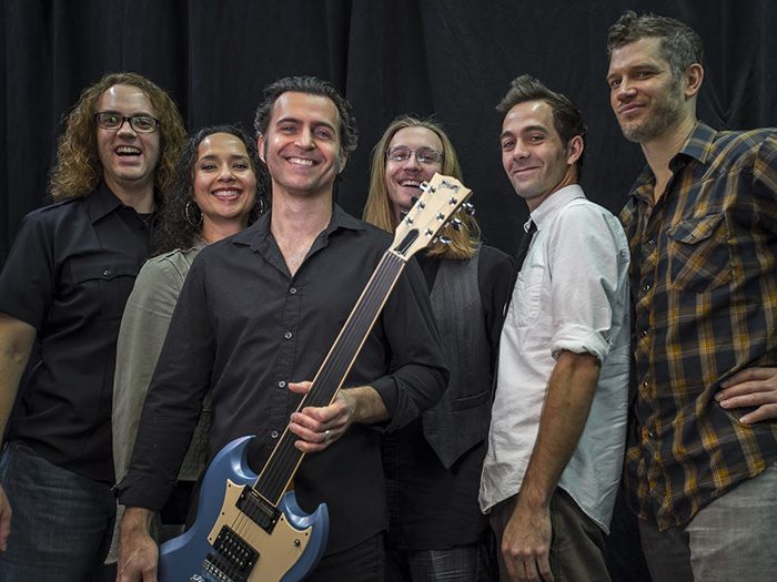 Band members smiling with electric guitar.