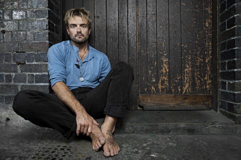Man sitting against a wooden door.